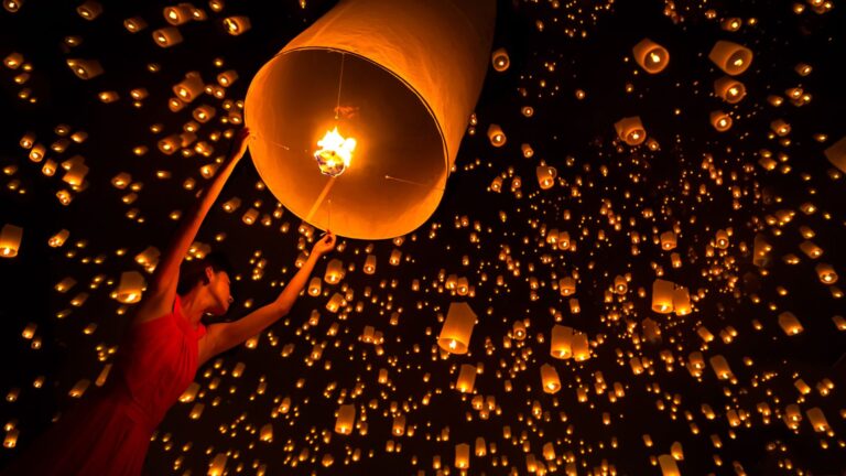 Linternas encendidas elevándose en el cielo nocturno durante el festival Yi Peng de Chiang Mai