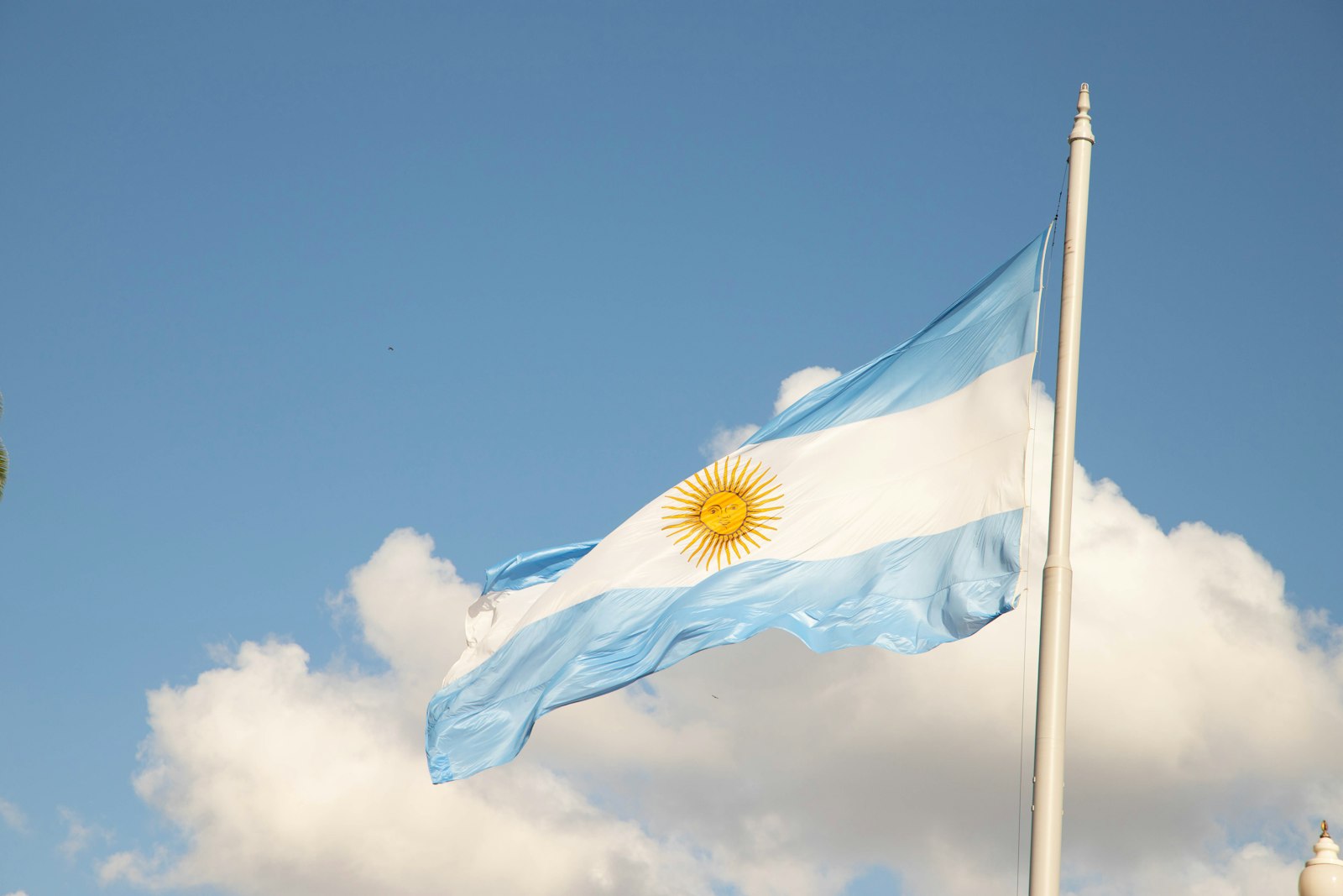 Bandera de Argentina ondeando al viento con una torre del reloj al fondo