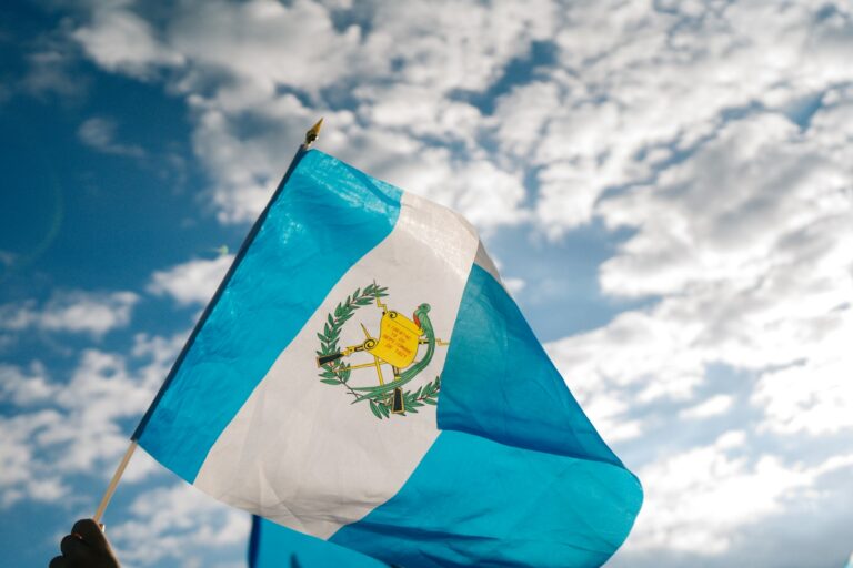 Bandera de Guatemala ondeando bajo un cielo con nubes