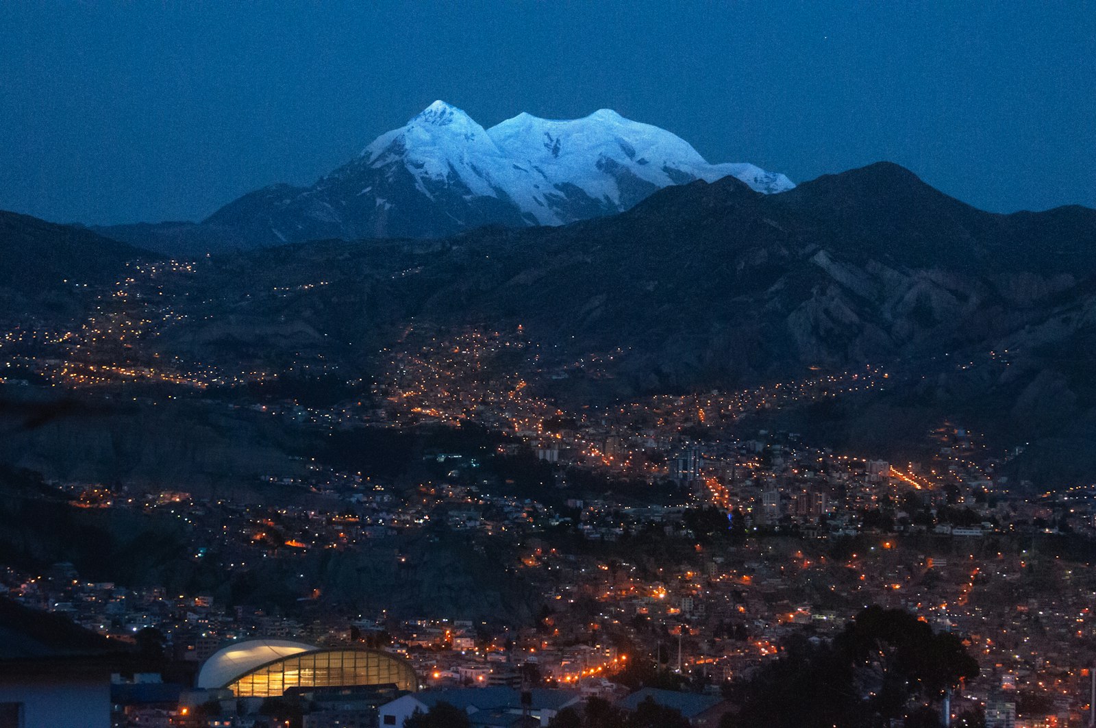 La Paz iluminada al anochecer con el nevado Illimani al fondo, en Bolivia
