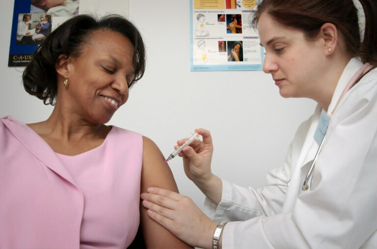 Una sanitaria pone una vacuna en el brazo a una mujer