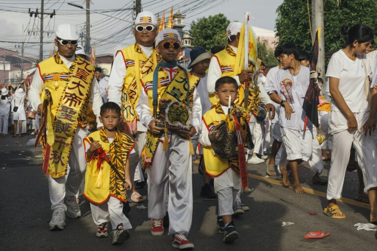 Participantes vestidos de blanco y amarillo en la procesión del Festival Vegetariano de Phuket