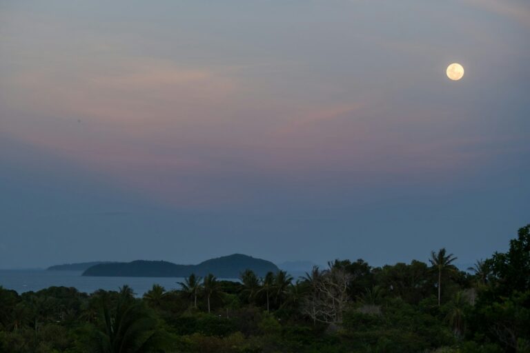 Luna llena sobre el mar y la costa al anochecer