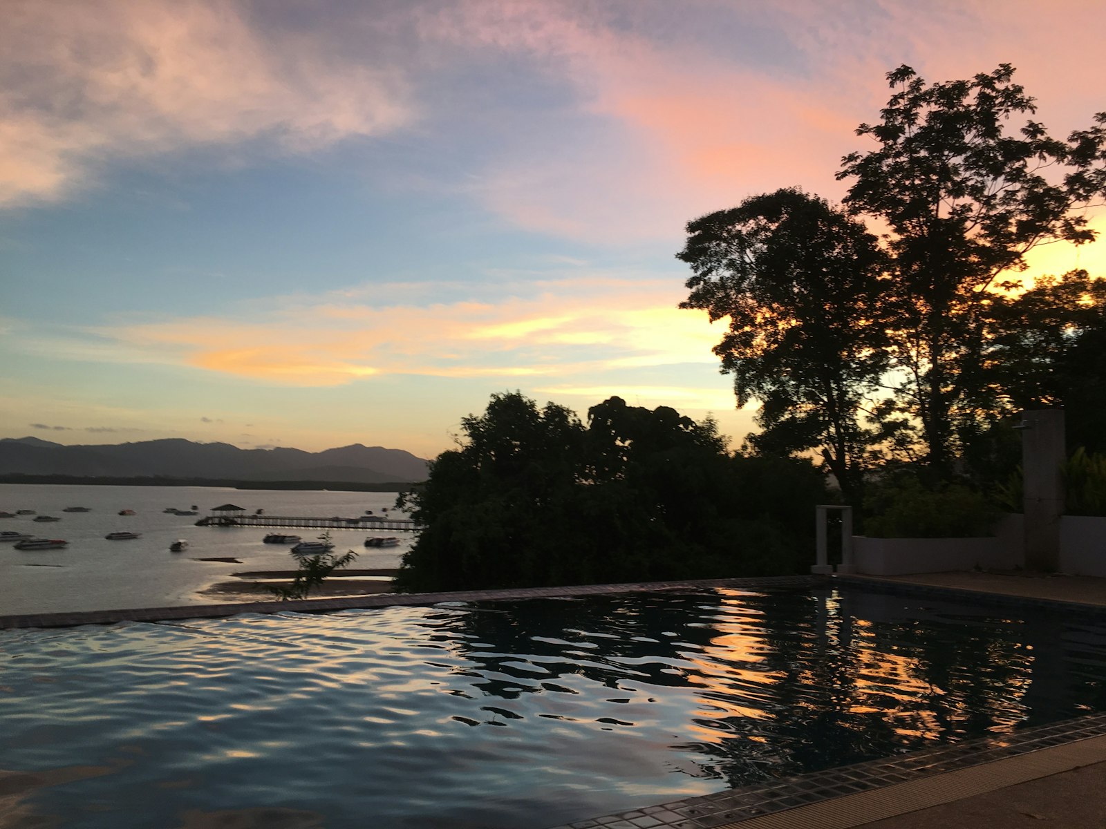 Piscina privada al atardecer con vistas a una bahía tropical