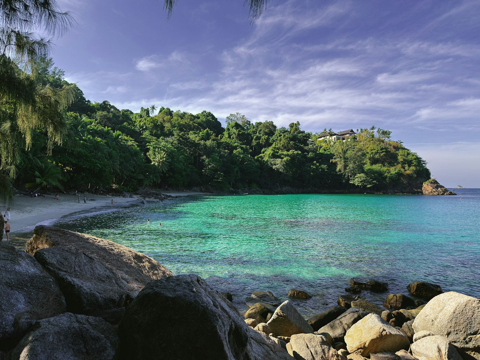 Cala de aguas turquesa con sol en la costa oeste de Phuket