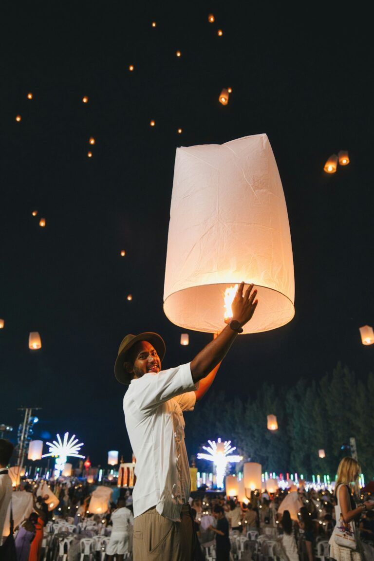 Joven soltando una linterna de papel encendida en el cielo nocturno de Tailandia