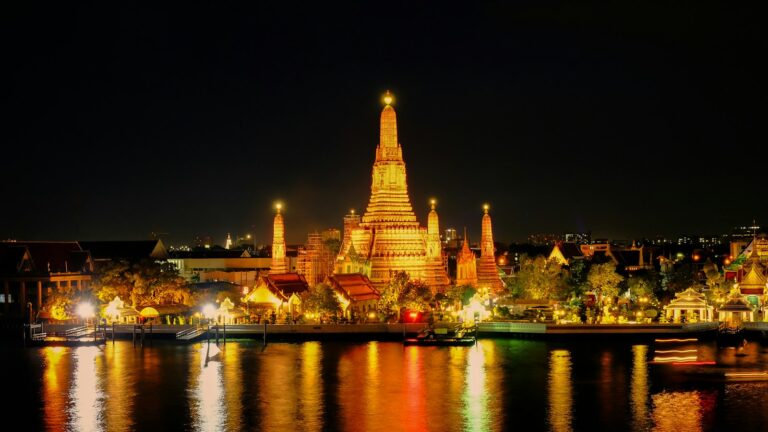 Templo de Wat Arun iluminado de noche y reflejado en el río Chao Phraya, en Bangkok